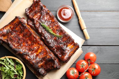 Biberiye, domates, sos ve salata ile servis edilen kızarmış domuz kaburgaları siyah ahşap masada, düz yatıyordu.