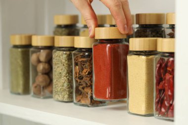 Kapalı mekanda kırmızı biber tozlu kavanoz alan kadın, yakın plan.