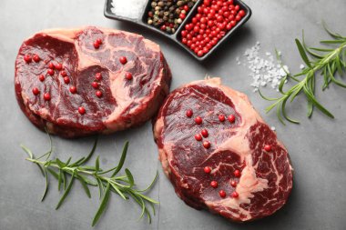 Çiğ et parçaları ve baharatlar gri dokulu masa üzerinde, düz yatıyordu.