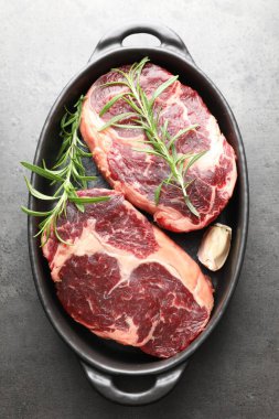 Çiğ et parçaları ve baharatlar gri desenli masa üzerinde fırın kabında, üst görünüm