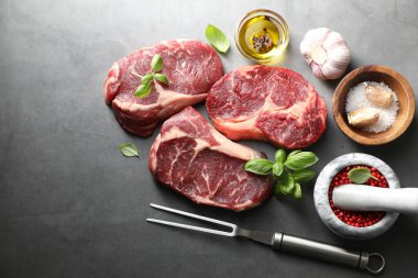Çiğ et, baharat ve çatal parçaları gri masada, düz yerde. Metin için boşluk