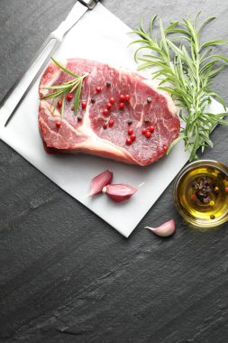 Bir parça çiğ et, baharat ve siyah masanın üzerine oyma çatal. Metin için boşluk