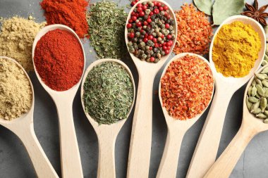 Gri masadaki kaşıklardaki farklı baharatlar düzdü.