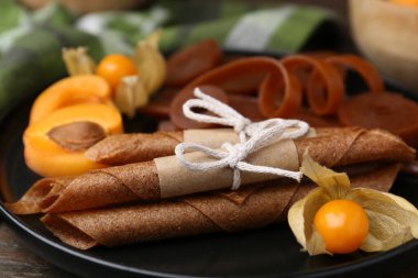 Lezzetli meyve derisi, bitki kökü ve kayısılar ahşap masada, yakın plan.