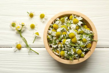Taze papatya çiçekleri ve kase beyaz ahşap masada, düz yatıyordu.