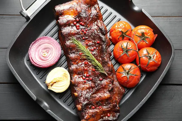 Biberiyeli domuz pirzolası, domates ve soğan. Gri ahşap masa, üst manzara.