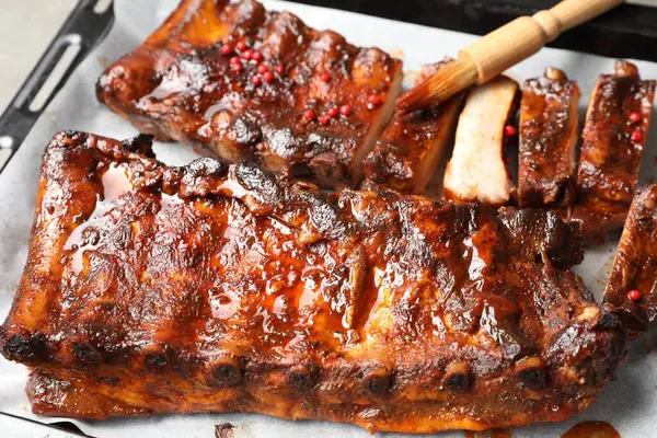 Fırçayla sosu pişirme tepsisindeki kaburgaların üzerine serpiştiriyorum.