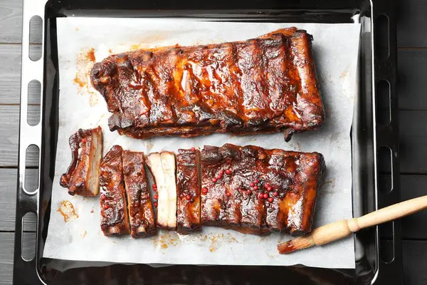 Lezzetli kaburgalar ve gri ahşap masadaki fırça, üst manzara.