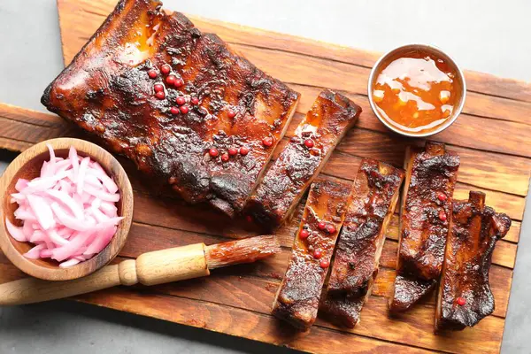 Lezzetli kaburgalar, sos, soğan ve fırça gri masada, üst manzara