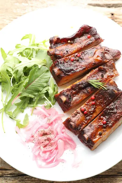 Lezzetli domuz pirzolası, roka ve soğan ahşap masa, üst manzara.