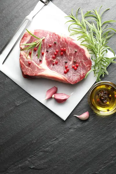 Bir parça çiğ et, baharat ve siyah masanın üzerine oyma çatal. Metin için boşluk