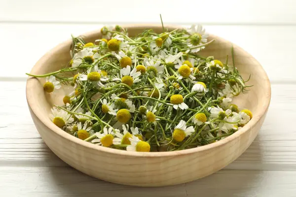 Taze papatya çiçekleri kasede beyaz ahşap masada, yakın plan.