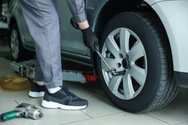 Tamirci araba servisinde lastik değiştiriyor, yakın plan.