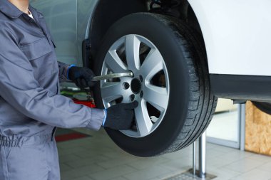 Tamirci araba servisinde lastik değiştiriyor, yakın plan.