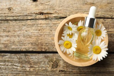 Ahşap masanın üstünde bir şişe yağ ve papatya çiçeği. Metin için boşluk