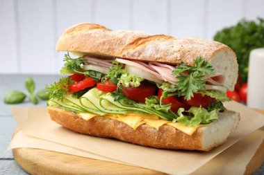 Jambonlu, peynirli ve sebzeli baget sandviç. Ahşap masa, gri arka plan, yakın plan.