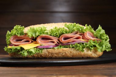 Jambonlu, peynirli ve sebzeli baget sandviç kahverengi arka planda, yakın planda.