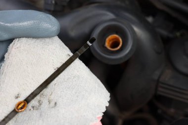 İşçi arabada motor yağı seviyesini dipstick ile kontrol ediyor.