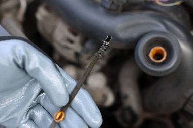 İşçi arabada motor yağı seviyesini dipstick ile kontrol ediyor.