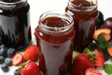 Kavanozlardaki farklı tatlı reçeller ve malzemeler masada, yakın plan.