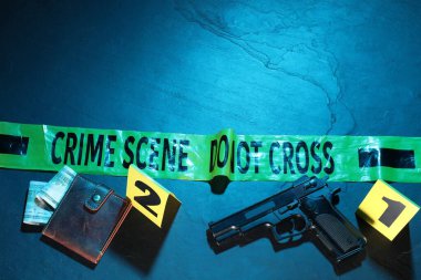 Adli tıp uzmanlığı. Deliller, işaretler, mavi arka planda polis bandı olan bir suç mahalli. Düz konum ve mesaj için yer. Renkli tonlama efekti