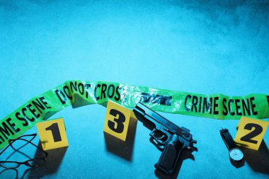 Adli tıp uzmanlığı. Deliller, işaretler, mavi arka planda polis bandı olan bir suç mahalli. Düz konum ve mesaj için yer. Renkli tonlama efekti
