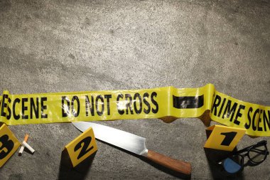 Adli tıp uzmanlığı. Gri arka planda delil, işaretler ve polis bandı olan bir suç mahalli. Metin için boşluk