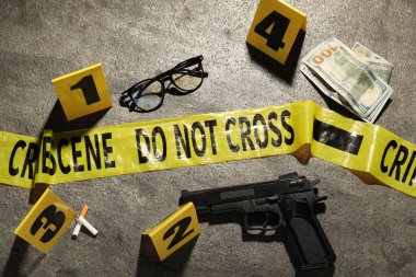 Adli tıp uzmanlığı. Gri arka planda delil, işaret ve polis bandı bulunan suç mahalli