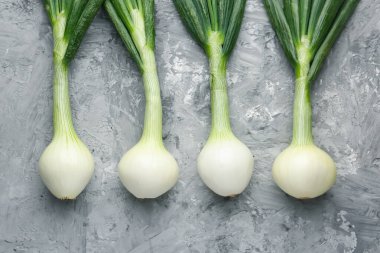 Taze taze yeşil soğanlar gri desenli masada, düz yerde.