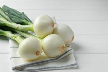 Taze taze soğan ve beyaz ahşap masada havlu, yakın plan.