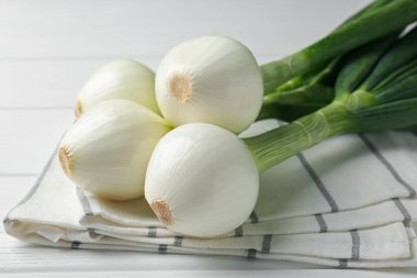 Taze taze soğan ve beyaz ahşap masada havlu, yakın plan.