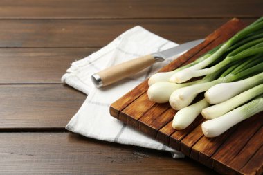 Taze taze soğanlar, tahta kesme tahtası ve bıçakla yakın plan. Metin için boşluk