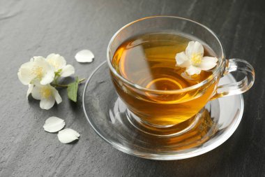 Aromatik yasemin çayı ve çiçekler gri masada, yakın plan.