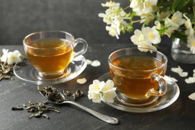 Aromatik yasemin çayı, bira ve çiçekler gri masada.