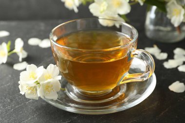 Aromatik yasemin çayı ve çiçekler gri masada, yakın plan.