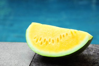 Dışarıdaki yüzme havuzunun yanında taş yüzeyde leziz bir karpuz dilimi, yakın plan.