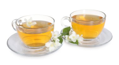 Cam fincanlar, çiçekler ve yeşil yapraklar içinde beyaz üzerine izole edilmiş yasemin çayı.