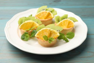 Meyveli tart ve açık mavi ahşap masada nane şekeri, yakın plan. Tatlı nefis.