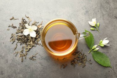 Cam bardakta Aromatik yasemin çayı, Gri masada bira ve çiçekler, düz uzanmış