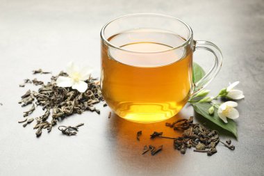 Cam bardakta Aromatik yasemin çayı, Gri masada bira ve çiçekler, yakın plan