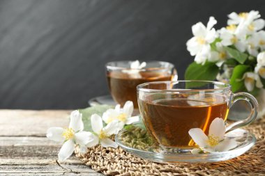 Cam bardaklarda yasemin çayı, ahşap masada çiçekler ve yeşil yapraklar, yakın plan. Metin için boşluk