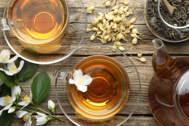 Aromatik yasemin çayı cam bardaklarda, çaydanlıkta, demlikte ve çiçeklerde ahşap masada, düz yerde.