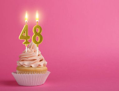 Pembe arka planda yanan mumları olan enfes bir kek. Mesaj için yer var. 48. yaş günü veya diğer özel günler