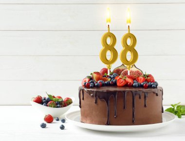Meyveli lezzetli çikolatalı pasta ve yanan numara şekilli mumlar masada, mesaj için yer var. 88. yaş günü veya diğer özel günler
