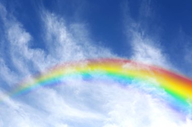 Mavi gökyüzünde parlak gökkuşağı güneşli bir günde bulutlarla