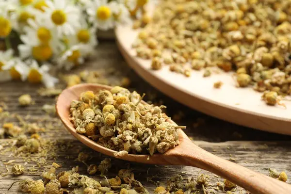 Tahta masada kaşıkta papatya çiçekleri, yakın plan.