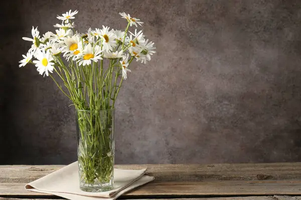 Tahta masadaki vazoda bir sürü güzel papatya çiçeği kahverengi desenli arka planda, yakın plan. Metin için boşluk