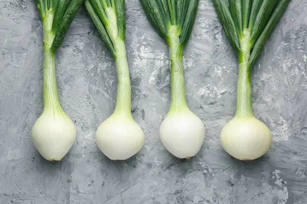 Taze taze yeşil soğanlar gri desenli masada, düz yerde.