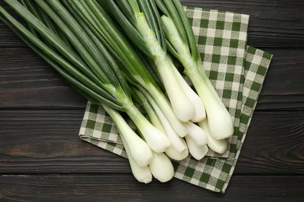 Taze taze soğan ve siyah ahşap masa üzerinde havlu.