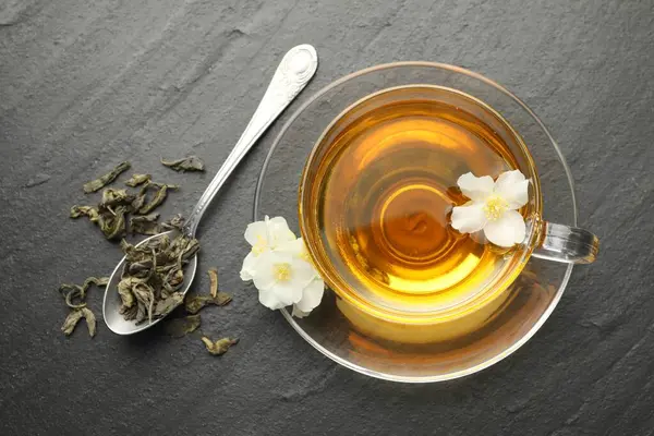 Aromatik yasemin çayı, bira ve çiçekler gri masada, düz uzanmış